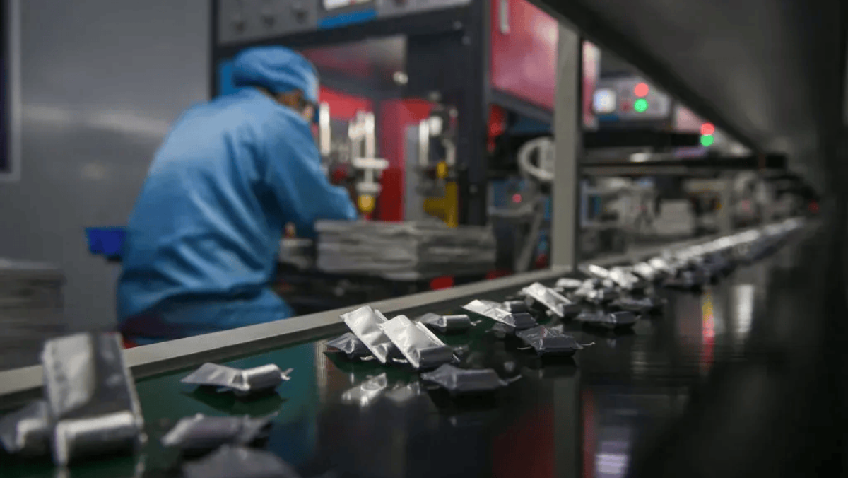 Wrapped battery materials moving along a factory conveyor system.